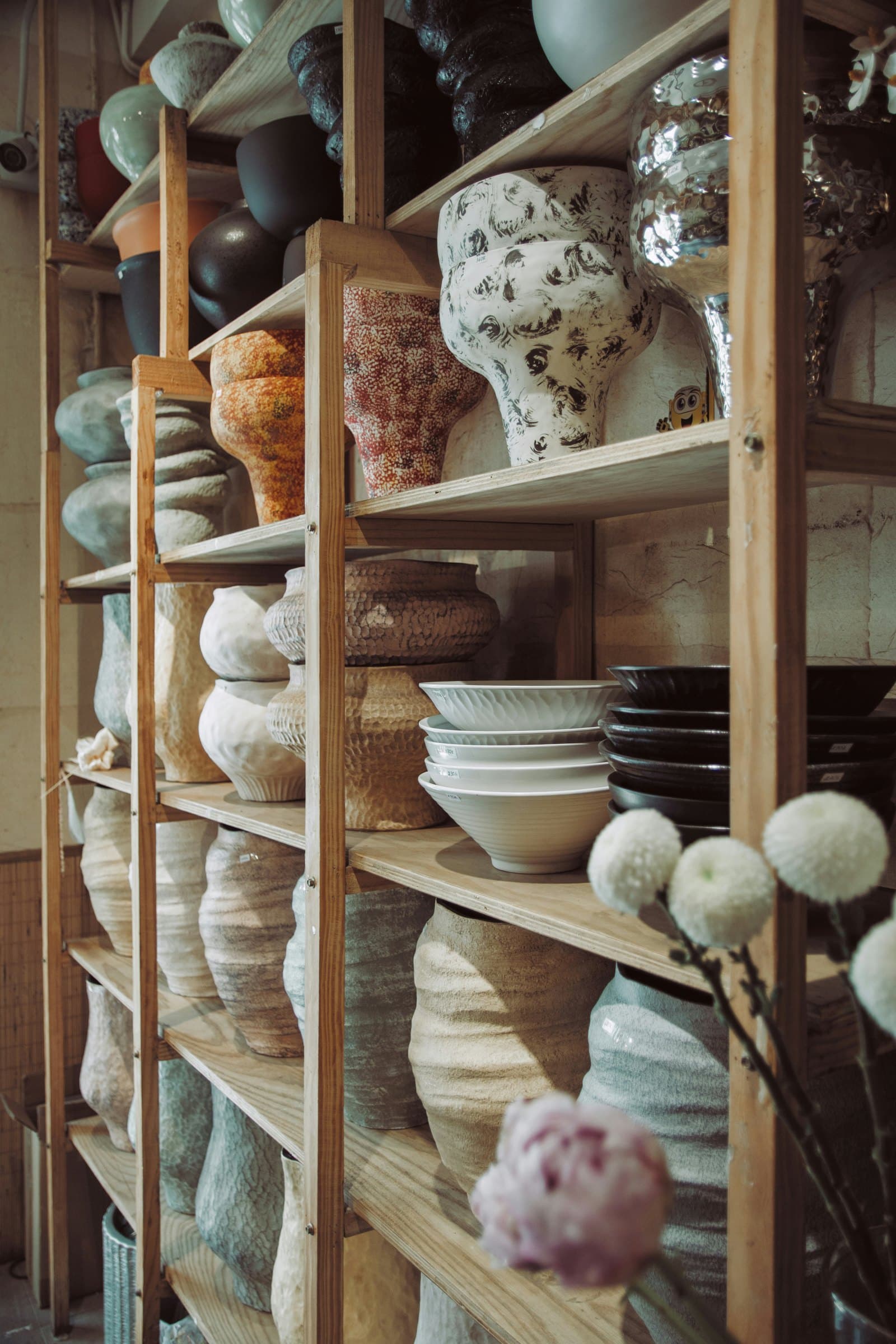 Shelves holding an assortment of decorative vases and floral vessels