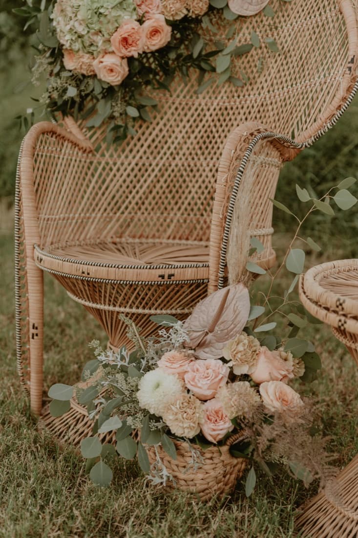 A wicker peacock chair styled with a blush floral arrangement