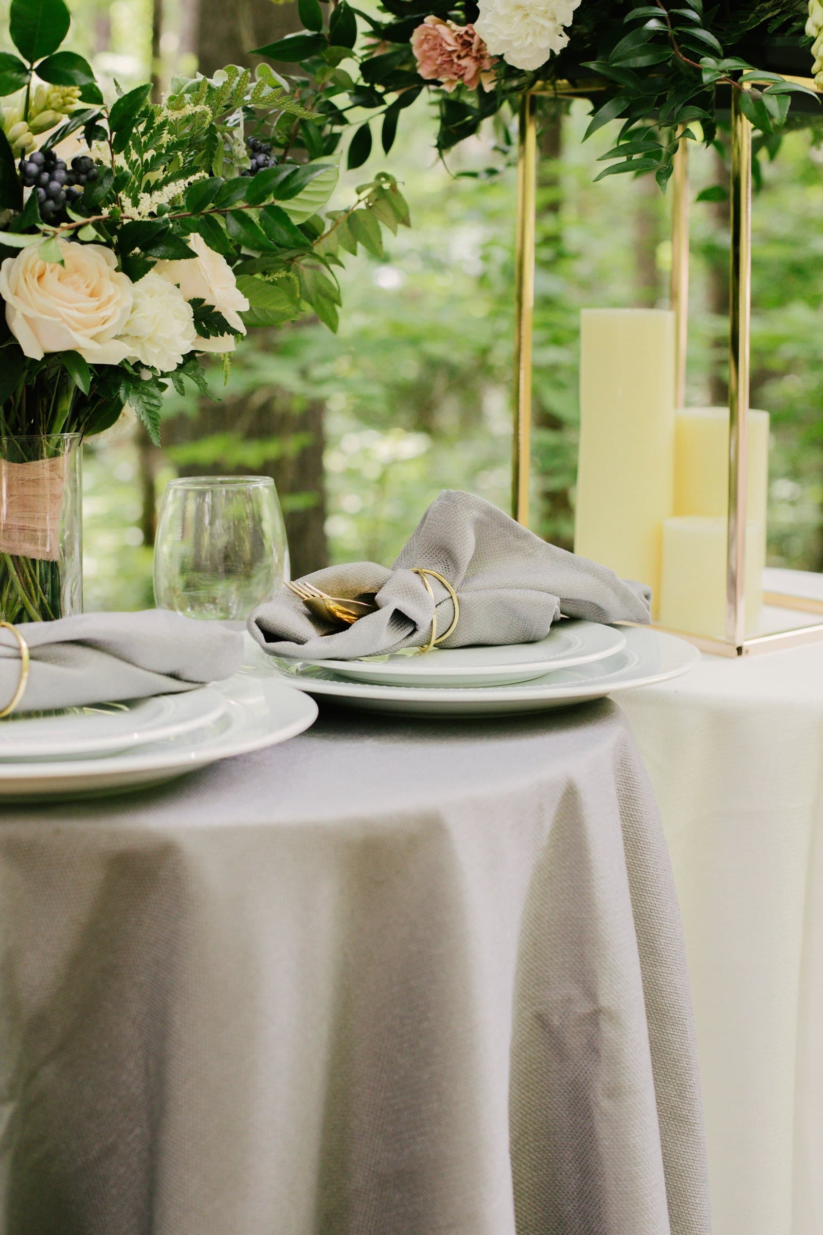 Wedding table with a white tablecloth, folded napkins, flowers, and candles