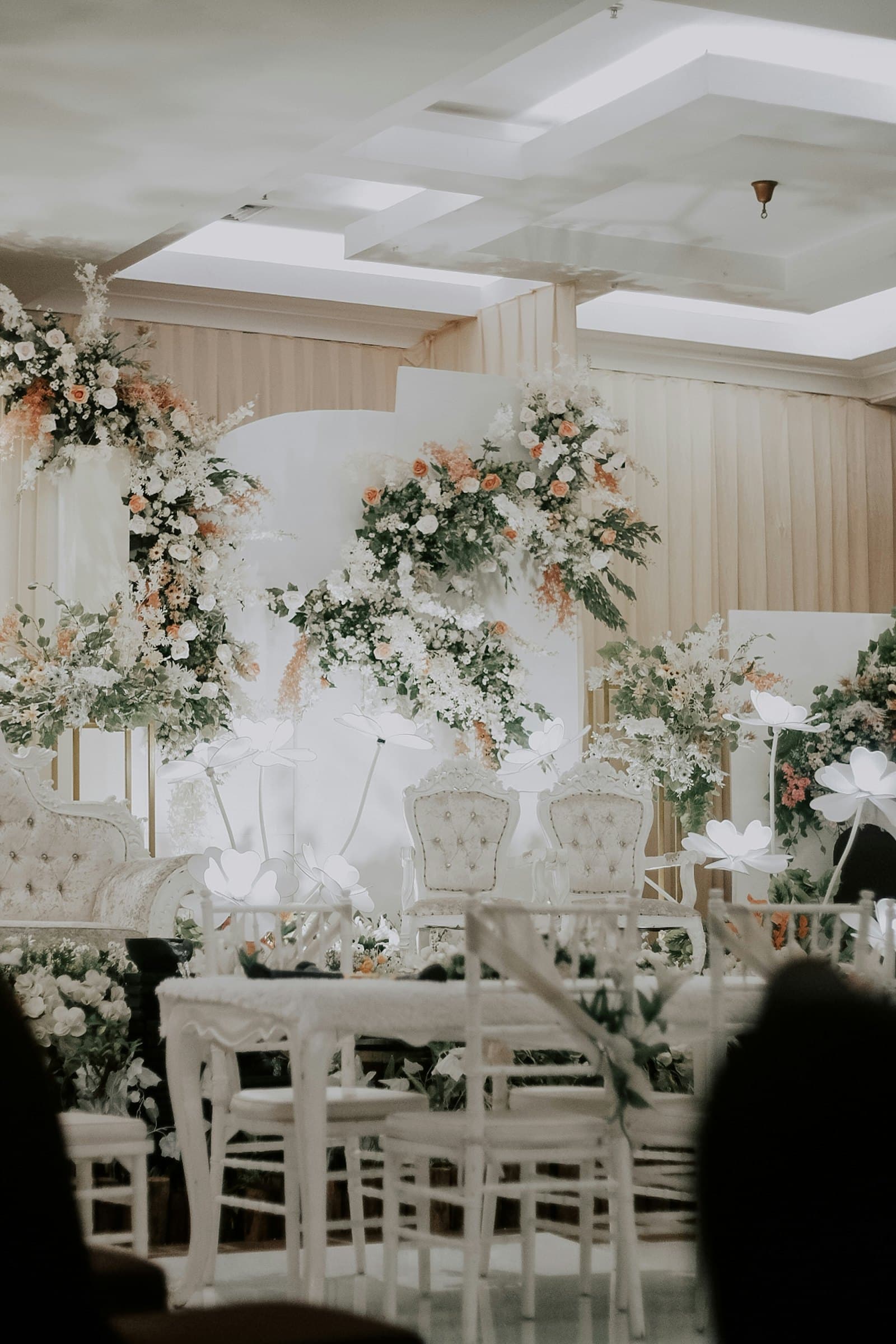 Wedding ceremony room with white chairs and large floral arrangements